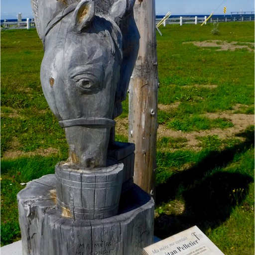 Sculpture of a woman holding a horse's head as it drinks. 