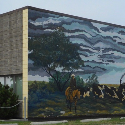 The mural on this building shows cattle in the foreground, grain in the background, the huge sky, grain elevators behind and the railway in the middle.